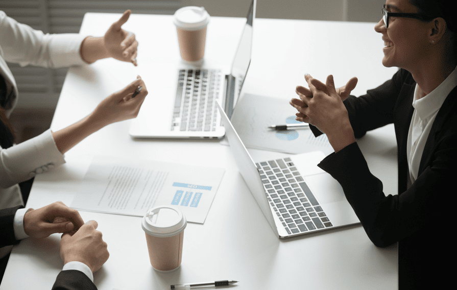 Diverse team in a meeting discussing data reports and laptops to plan a high-converting content localization strategy.
