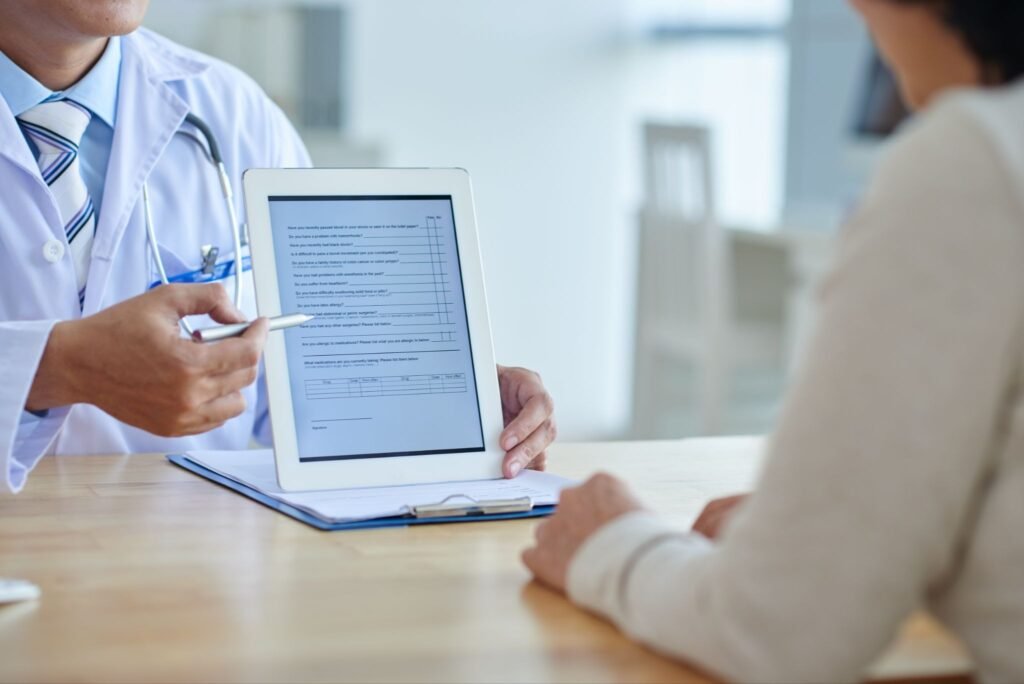 Doctor discussing a medical form on a tablet with a patient during a consultation