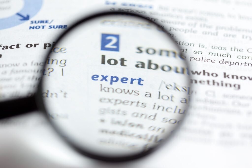 Close-up shot of a magnifying glass enlarging the word "expert", symbolizing the necessity of specialized expertise in a reliable patent translation process.