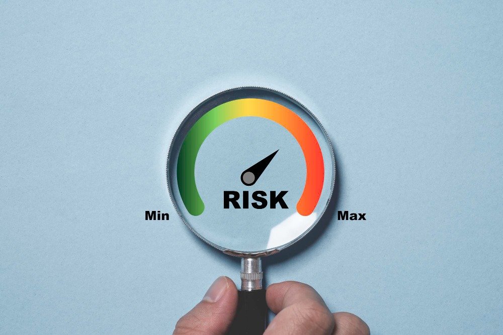A hand holding a magnifying glass over a risk meter gauge pointing toward high risk, representing the outsized legal risks in translation.