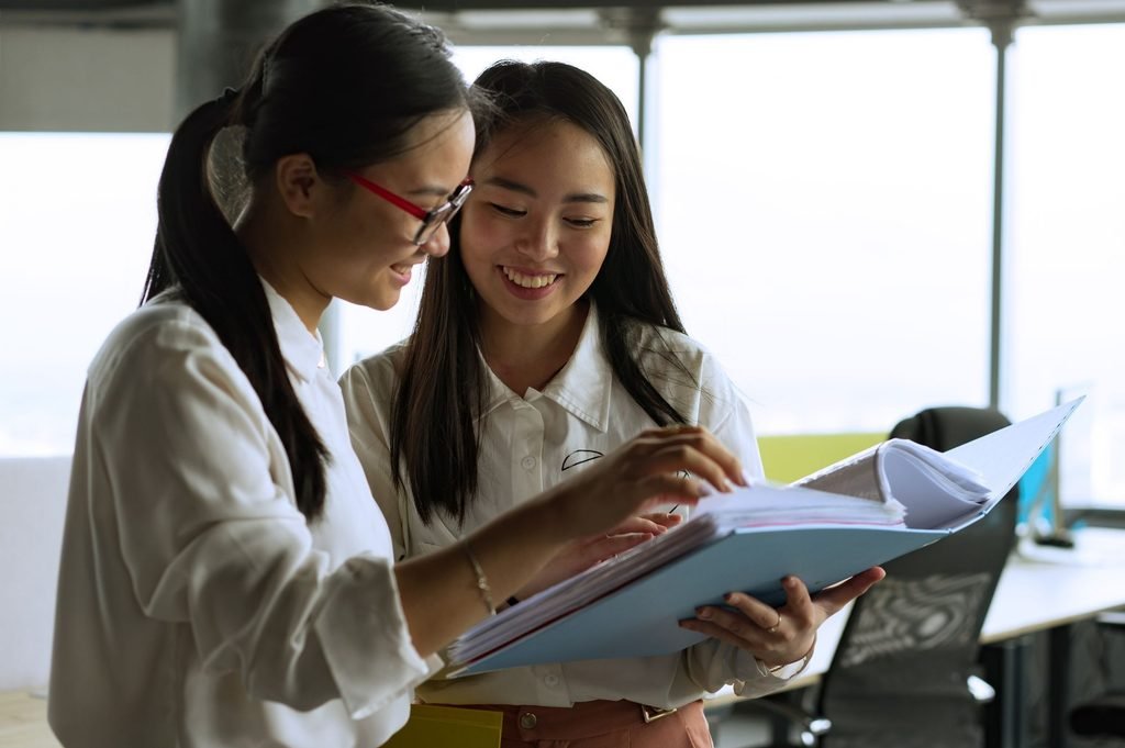 Two colleagues examine documents to ensure they are ready for final delivery.