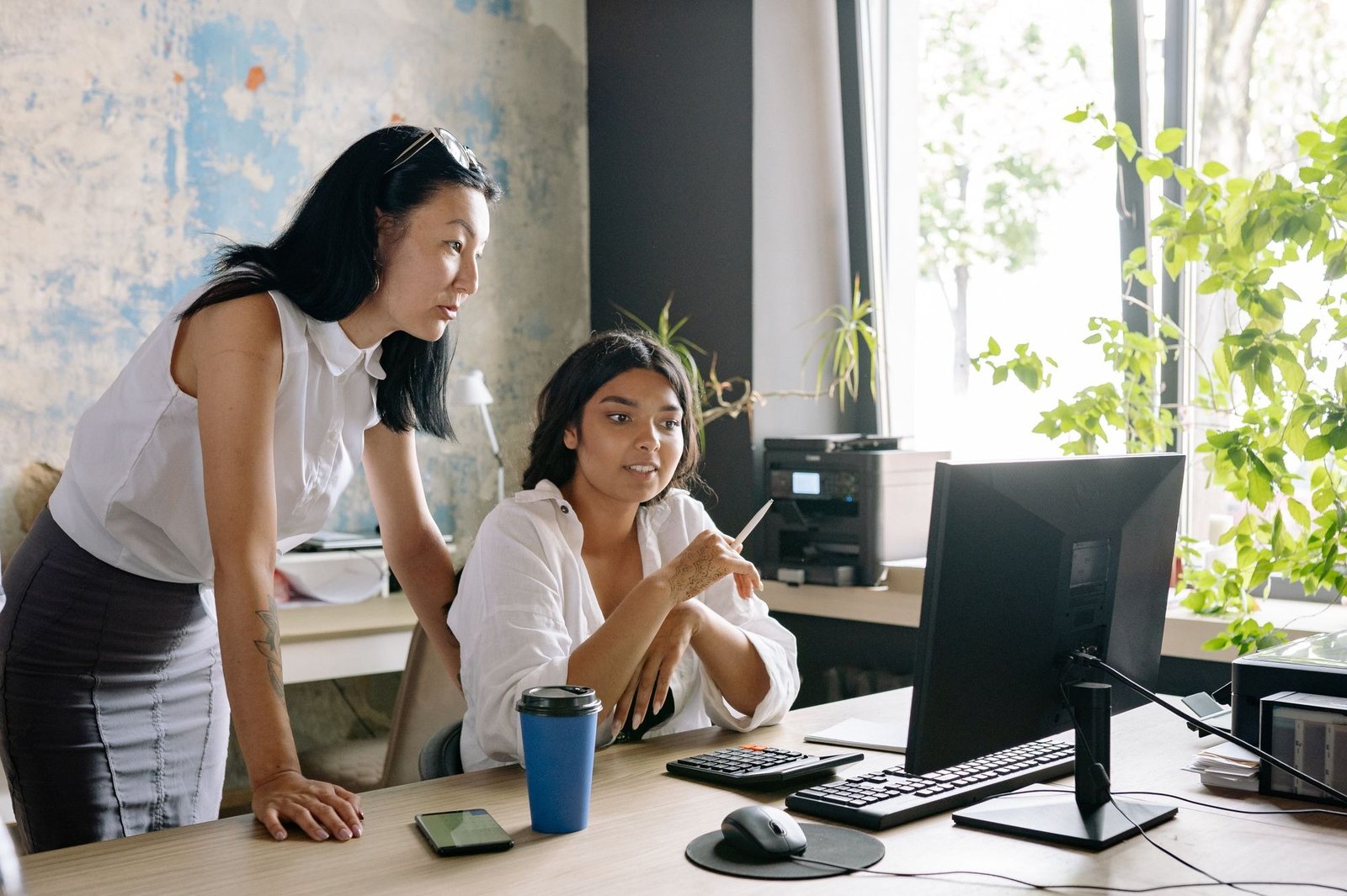 Two professionals discussing machine translation post-editing turnaround metrics in front of a monitor.